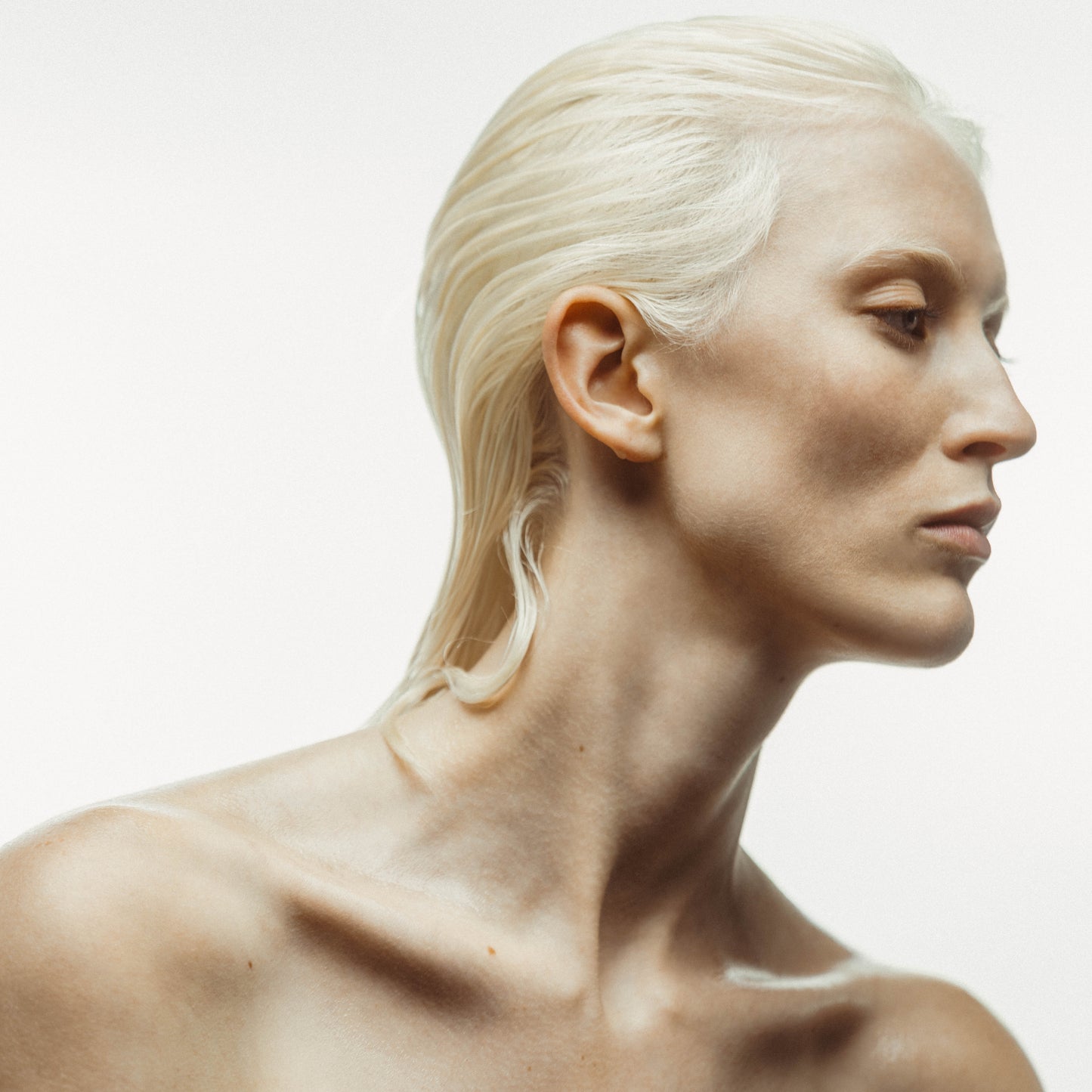 Une jeune femme aux cheveux décolorés pose avec élégance, mettant en valeur ses mèches brillantes et bien entretenues, grâce à l'utilisation de l'Huile sérum pour cheveux nourris. Cette photo illustre les bienfaits d'un produit de soin capillaire pour des cheveux décolorés ou abîmés.