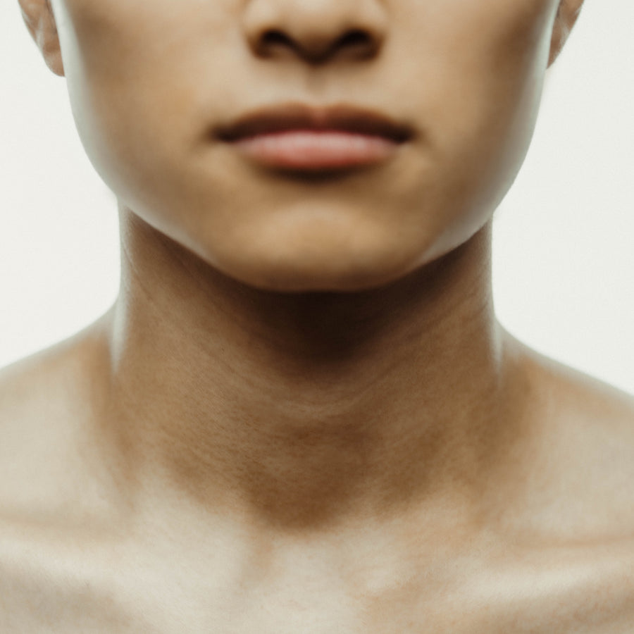 Une personne d'origine asiatique est mise en avant dans cette photo, avec un focus sur la partie supérieure de son corps. Sa peau rayonne d'une lueur naturelle grâce à l'application de l'Huile sérum pour cheveux. Cette image met en valeur les bienfaits du produit, créant une peau radieuse et saine.